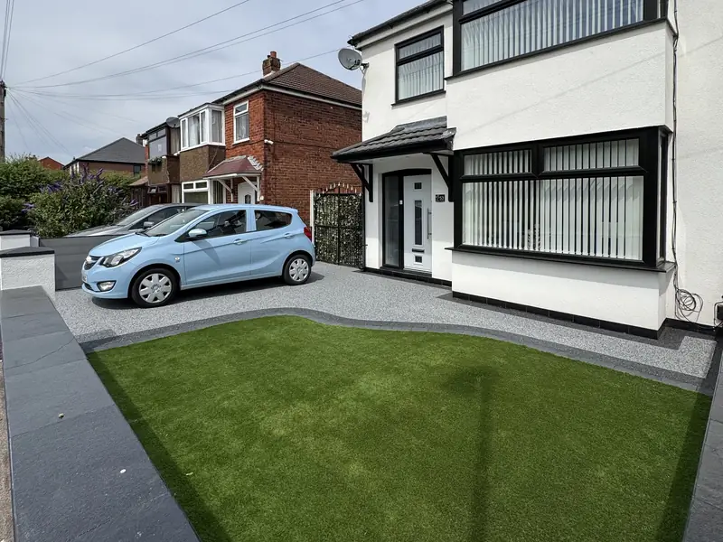 Silver grey resin bound driveway with a dark border beside artificial grass