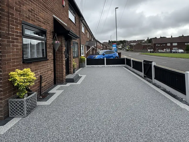 Grey resin bound driveway with a contrasting light border outside a brick terrace