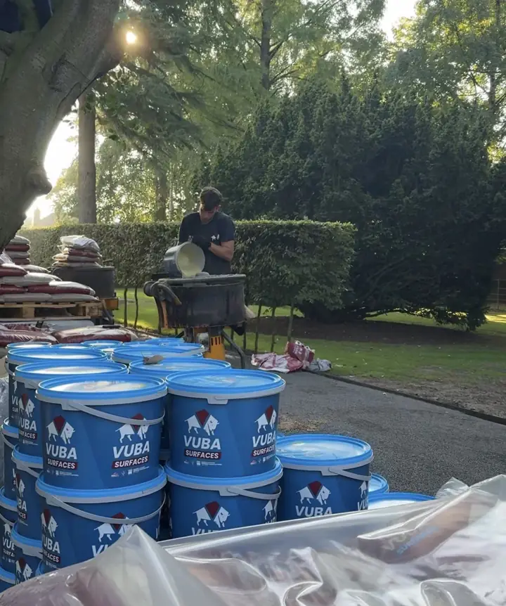 T&A Resin installer pouring Vuba resin into the mixer beside stacked Vuba tubs